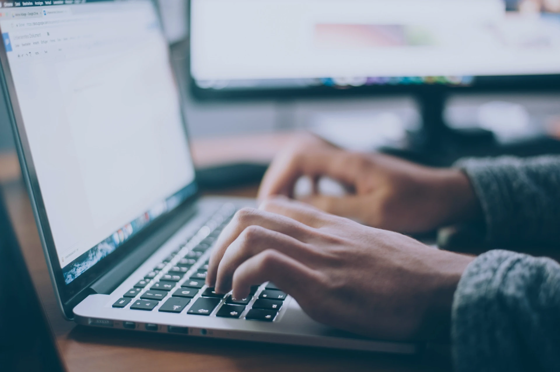 A person sitting at a desk and writing a blog post on a laptop